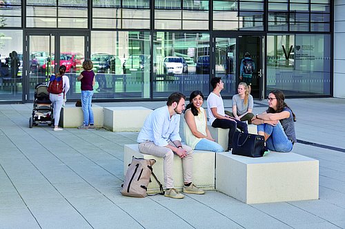 Studierende sitzen vor dem Gebäude VW am Campus Grifflenberg